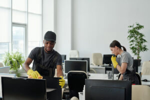 diverse staff of modern commercial cleaning service company wiping computer monitor